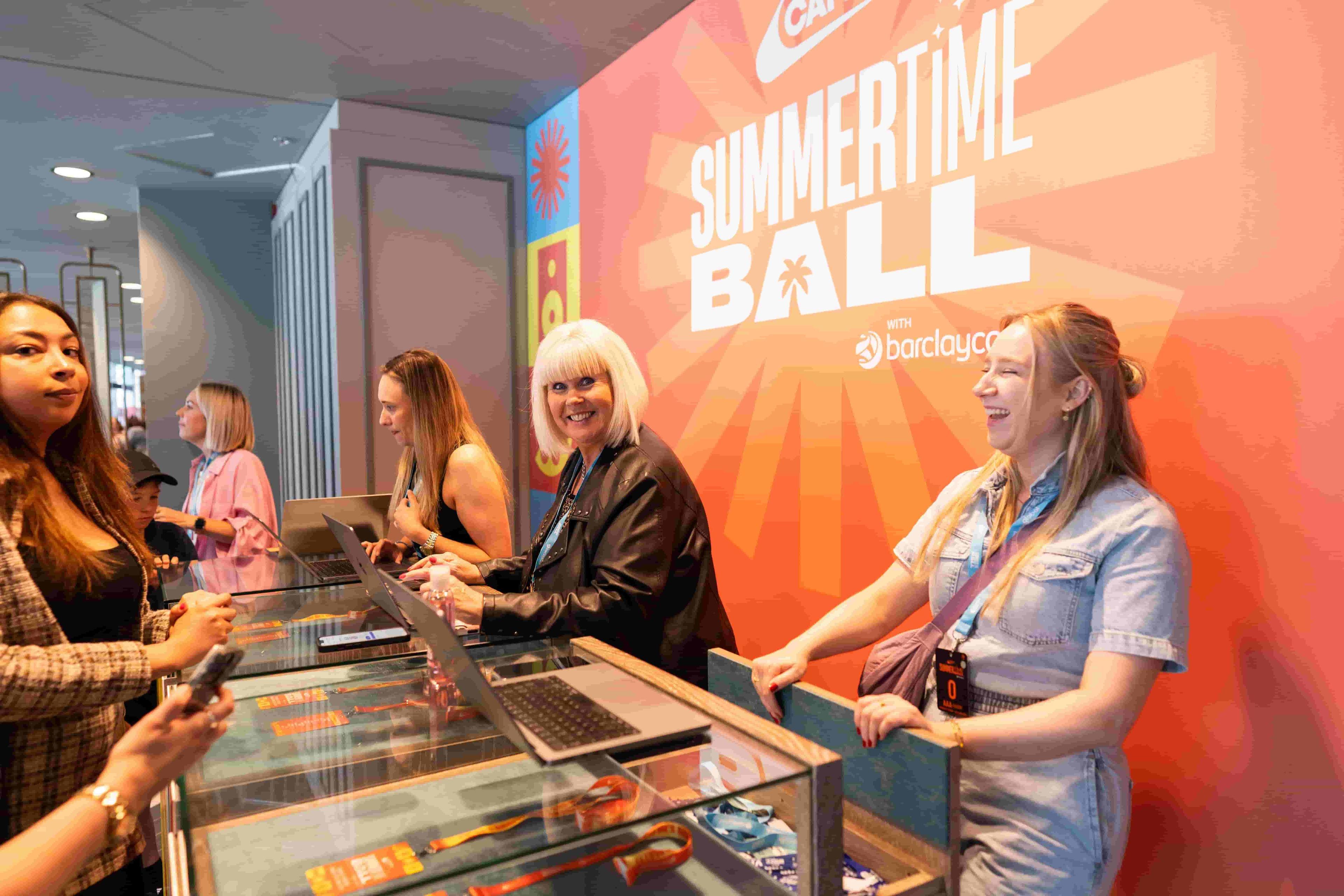 People smiling and engaging around a table in a store setting during a corporate event.