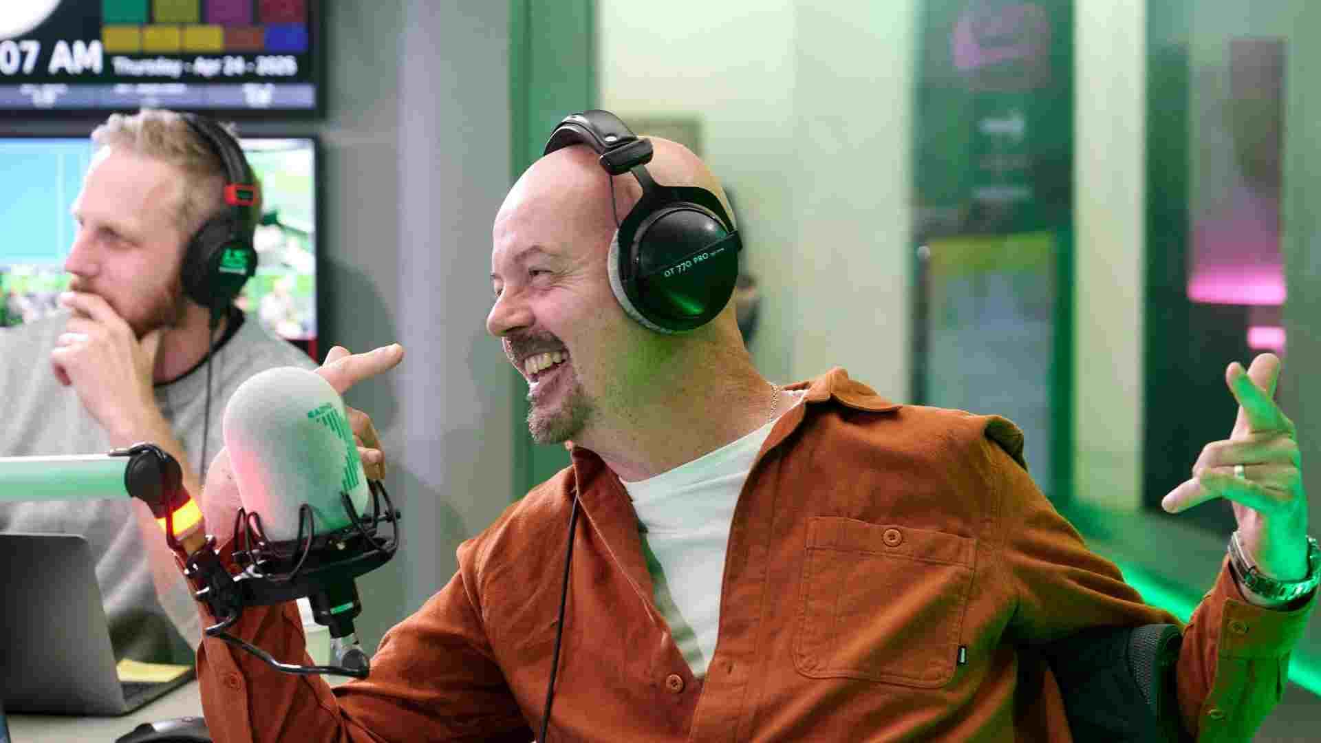 Smiling man with headphones on in a radio studio